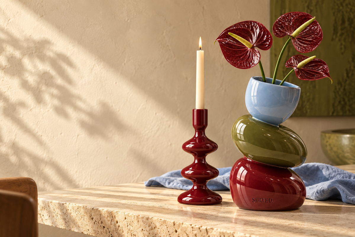SERVED. Off Balance-vaas en burgundy kandelaar op een warme beige tafel met lichtblauw linnen.